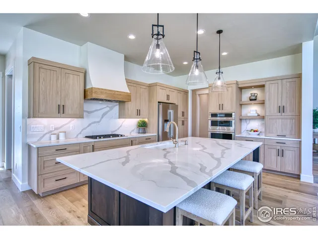 a kitchen with stainless steel appliances kitchen island granite countertop a table chairs and a refrigerator