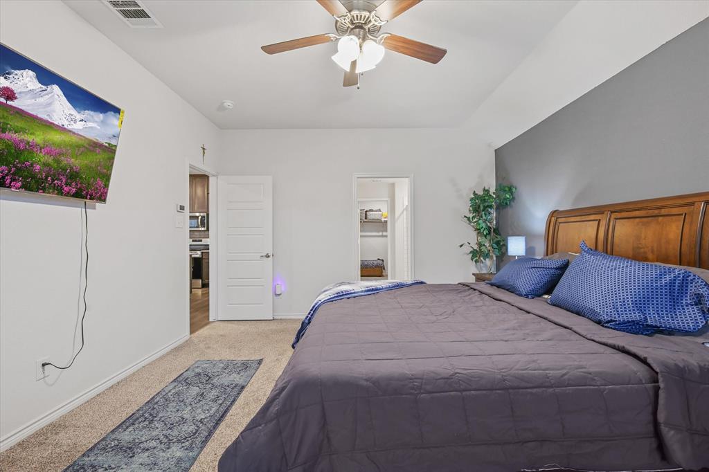 1653 Albatross Road Princeton, TX 75407 - Photo 12 of 18 a bedroom with a large bed and a chandelier