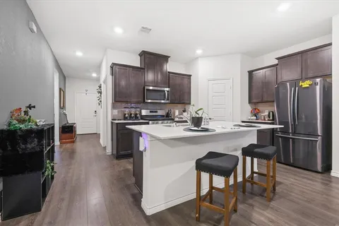 a kitchen with stainless steel appliances a refrigerator a stove a sink dishwasher and white cabinets with wooden floor