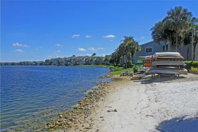 a view of a lake with lawn chairs and wooden fence