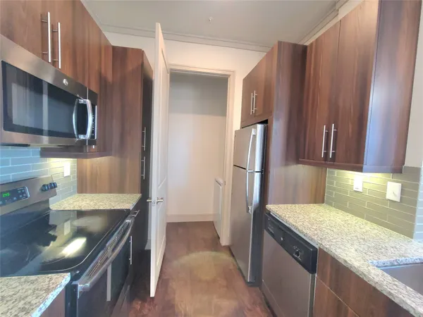 a kitchen with stainless steel appliances granite countertop a refrigerator a stove and a sink with wooden cabinets