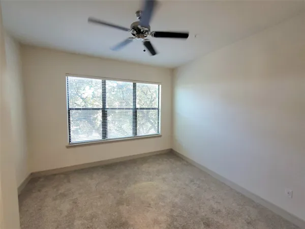 an empty room with a window and a fan