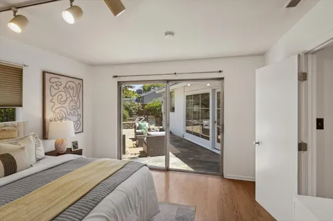 a bedroom with a bed and a large window with wooden floor