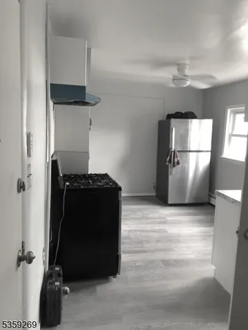 a view of a refrigerator in kitchen and an empty room