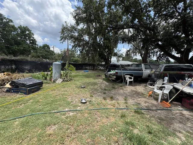 a view of a backyard with table and chairs with a fire pit and two trees