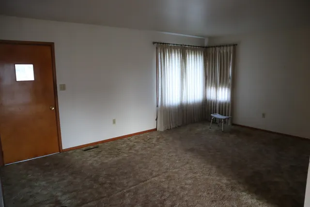 an empty room with window and closet area