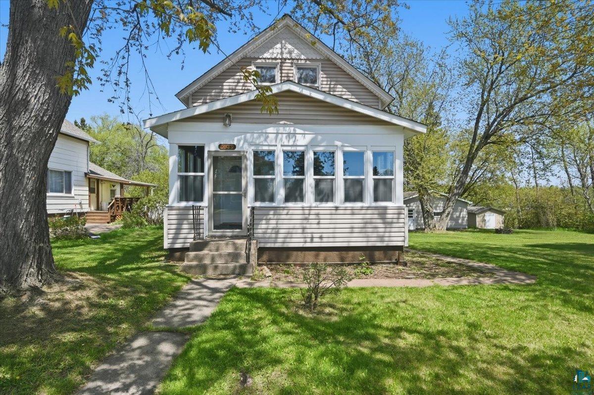 Traditional-style residence featuring horizontal siding, a multi-pane enclosed porch, and a dormer window