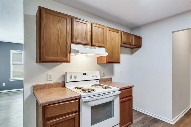 a kitchen with stainless steel appliances wooden floor sink stove and cabinets