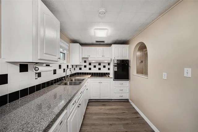 a kitchen with granite countertop a sink a counter top space cabinets and stainless steel appliances