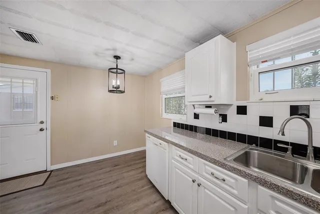 a kitchen with stainless steel appliances granite countertop white cabinets a sink a stove and wooden floor