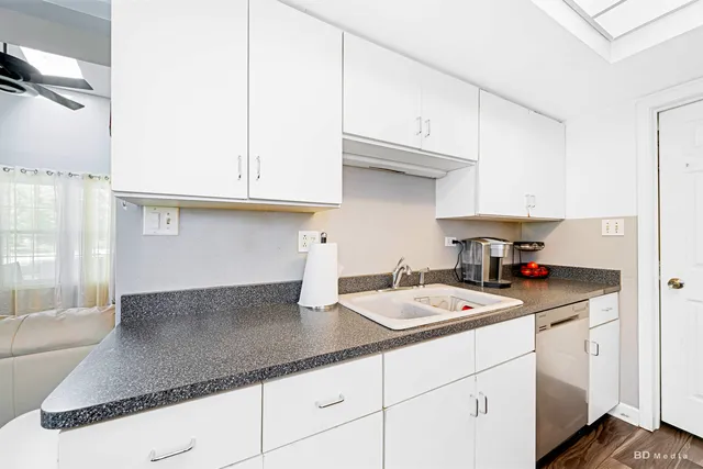 a kitchen with stainless steel appliances granite countertop a sink a stove and white cabinets