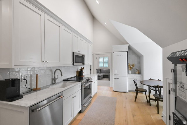180 Farm Road Midway, UT 84049 - Photo 80 of 99 Vaulted ceiling kitchen featuring white shaker cabinetry, stainless steel appliances, a white farmhouse sink, and light wood-finish flooring