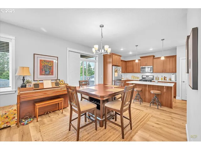 a dining hall with stainless steel appliances kitchen island granite countertop a dining table chairs and a refrigerator