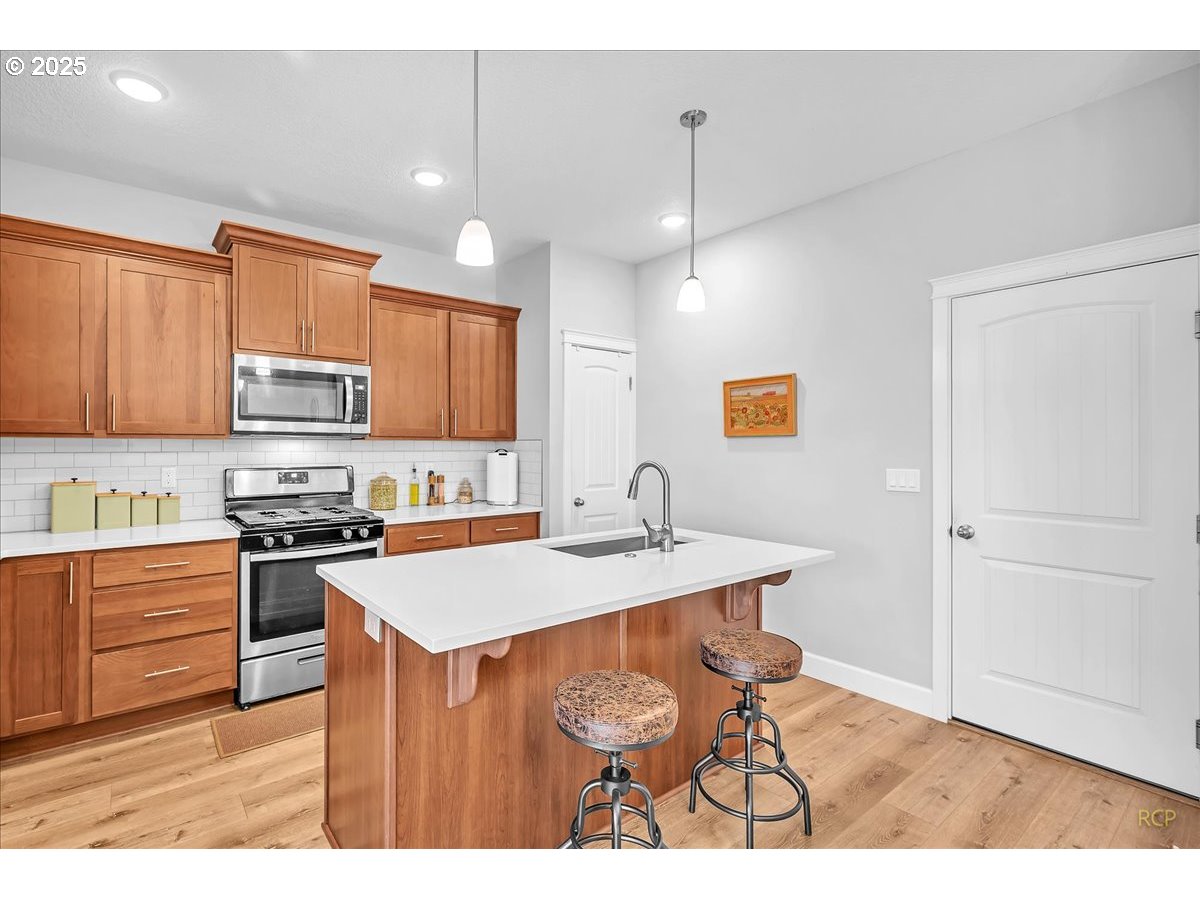 35560 Valley View Drive St. Helens, OR 97051 - Photo 22 of 47 a kitchen with stainless steel appliances granite countertop a sink a stove a refrigerator a microwave oven with white cabinets and wooden floor