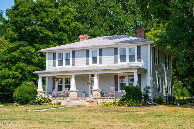 a view of a house with potted plants and a large tree