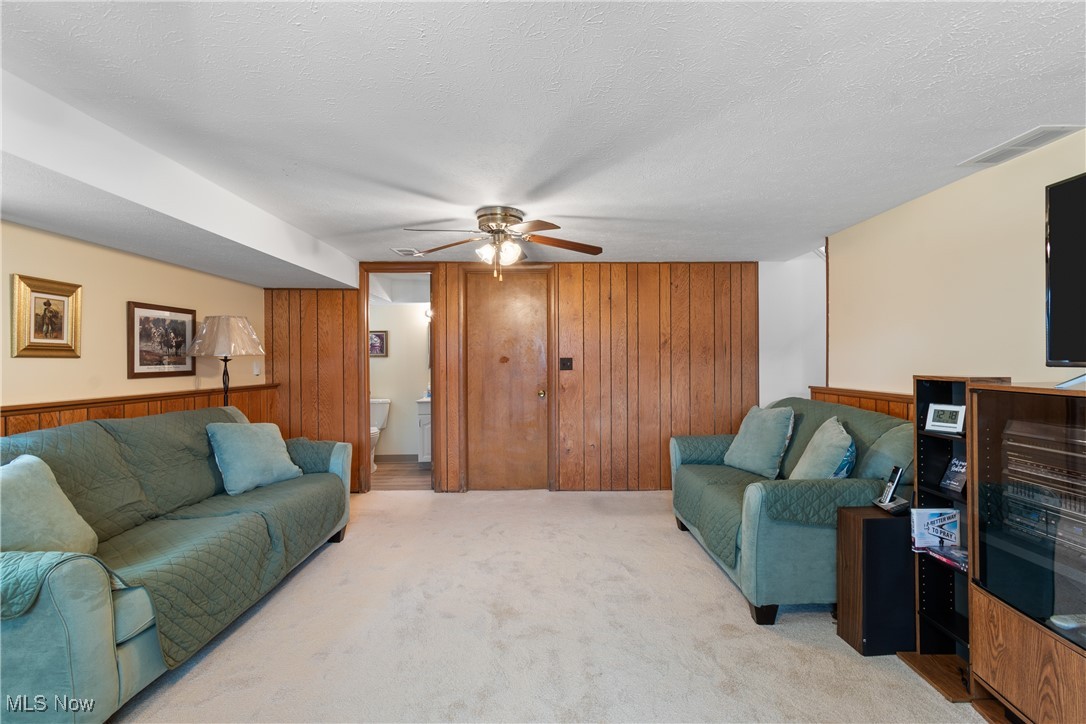 447 Center Road Bedford, OH 44146 - Photo 25 of 33 Living area featuring light carpet, visible vents, ceiling fan, a textured ceiling, and wood walls