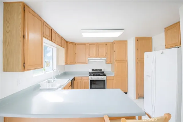 a kitchen with a refrigerator a stove top oven a counter space and a window