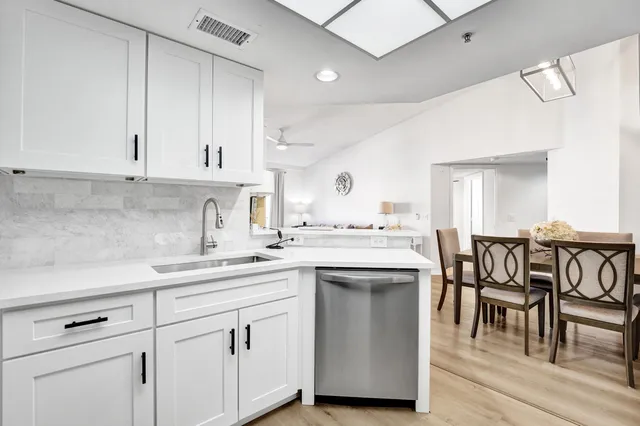 a kitchen with a sink white cabinets and white appliances