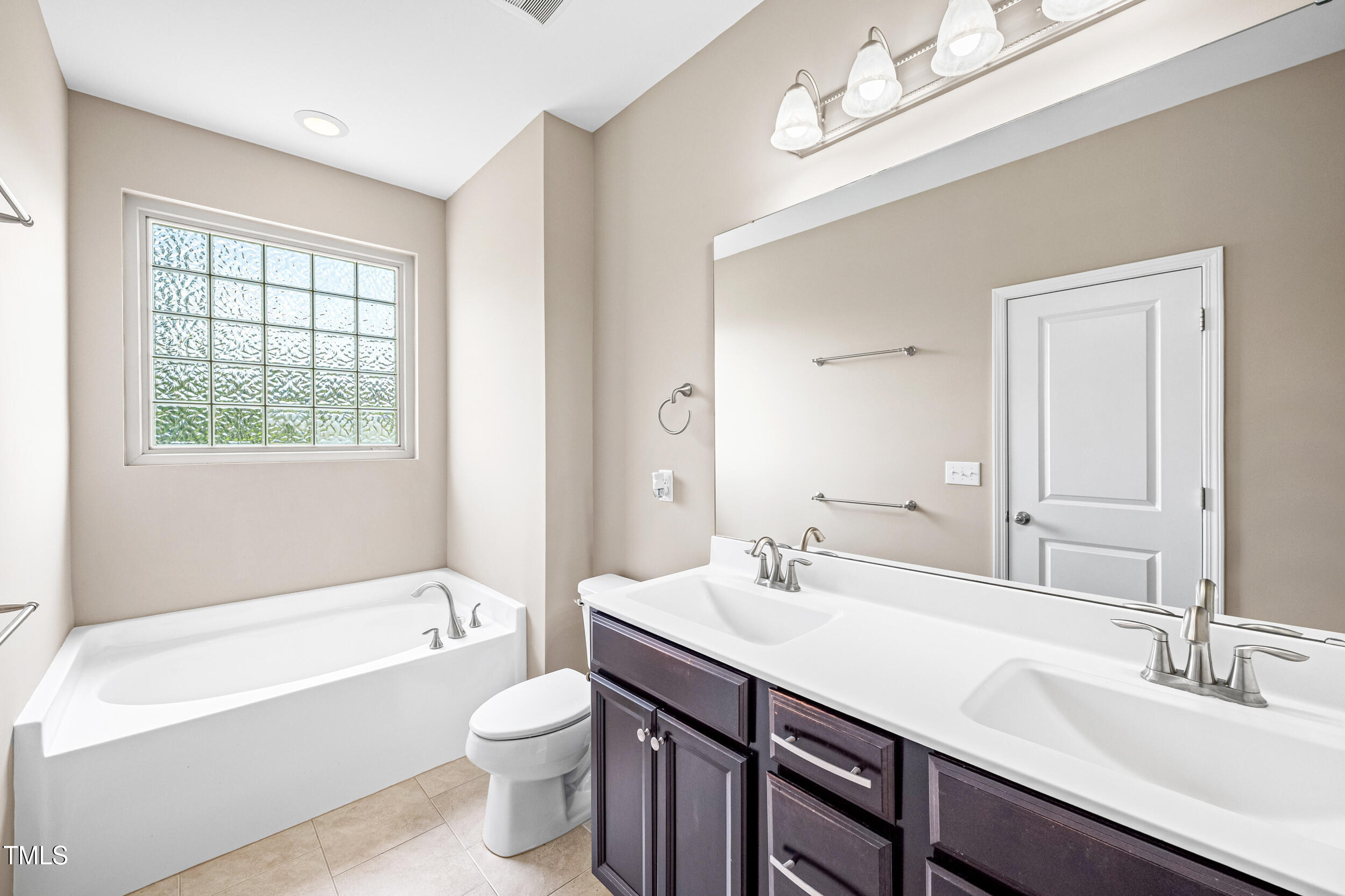 677 Wickham Ridge Road Apex, NC 27539 - Photo 23 of 34 a bathroom with a double vanity sink and a bathtub