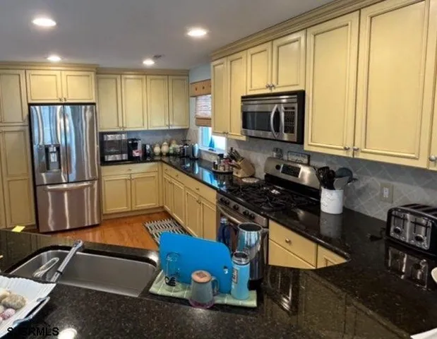 a kitchen with stainless steel appliances granite countertop a stove top oven a sink dishwasher and cabinets with wooden floor