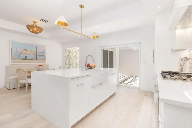 a large white kitchen with a stove a sink a dining table and chairs