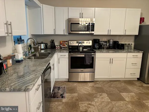 a kitchen with stainless steel appliances granite countertop a stove and a white cabinets