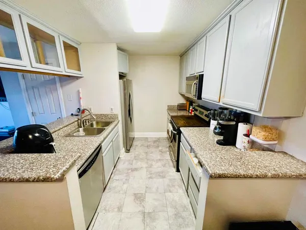 a kitchen with granite countertop sink stove and cabinets
