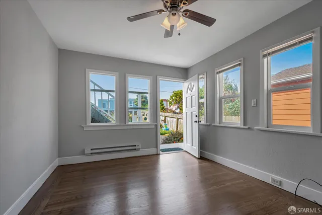 a view of an empty room with a window and wooden floor