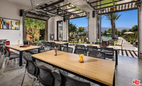 a dining hall with couches a dining table and chairs with outer view