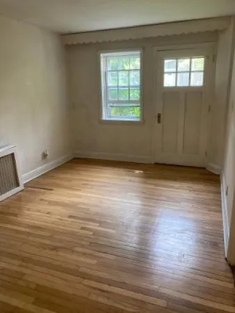 a view of an empty room with wooden floor and a window