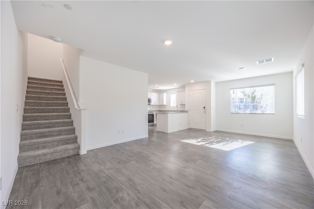 12185 Scarlet Ember Road, Unit 4 Las Vegas, NV 89183 - Photo 3 of 40 Unfurnished living room with stairway, dark wood-style flooring, and recessed lighting