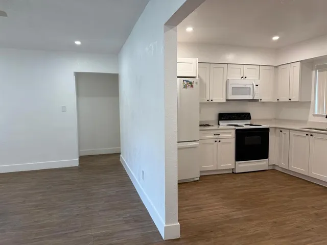a kitchen with cabinets wooden floor and stainless steel appliances