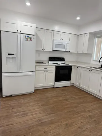 a kitchen with stainless steel appliances white cabinets and wooden floors