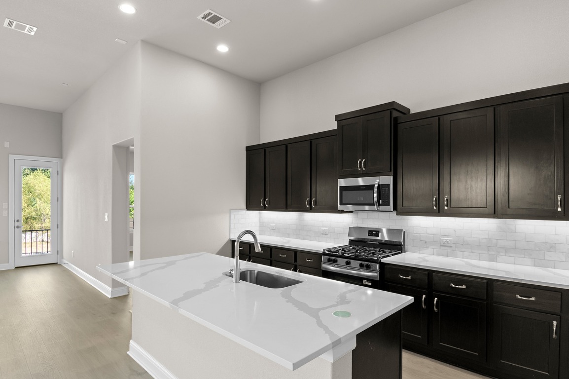 600 C-Bar Ranch Trail, Unit 122 Cedar Park, TX 78613 - Photo 17 of 31 a kitchen with a sink and a stove top oven with wooden floor