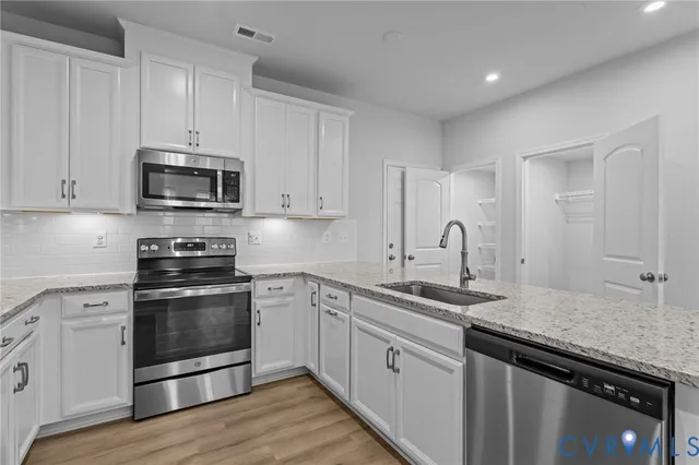 a kitchen with granite countertop white cabinets and stainless steel appliances