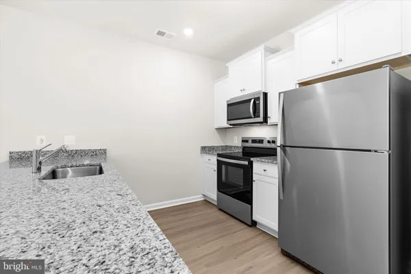 a kitchen with stainless steel appliances granite countertop a stove microwave and refrigerator
