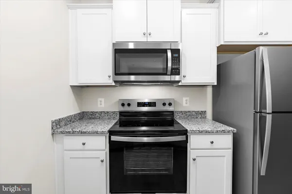 a kitchen with granite countertop cabinets stainless steel appliances and wooden floor