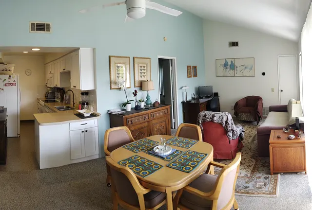 a living room with furniture a rug kitchen view and a table