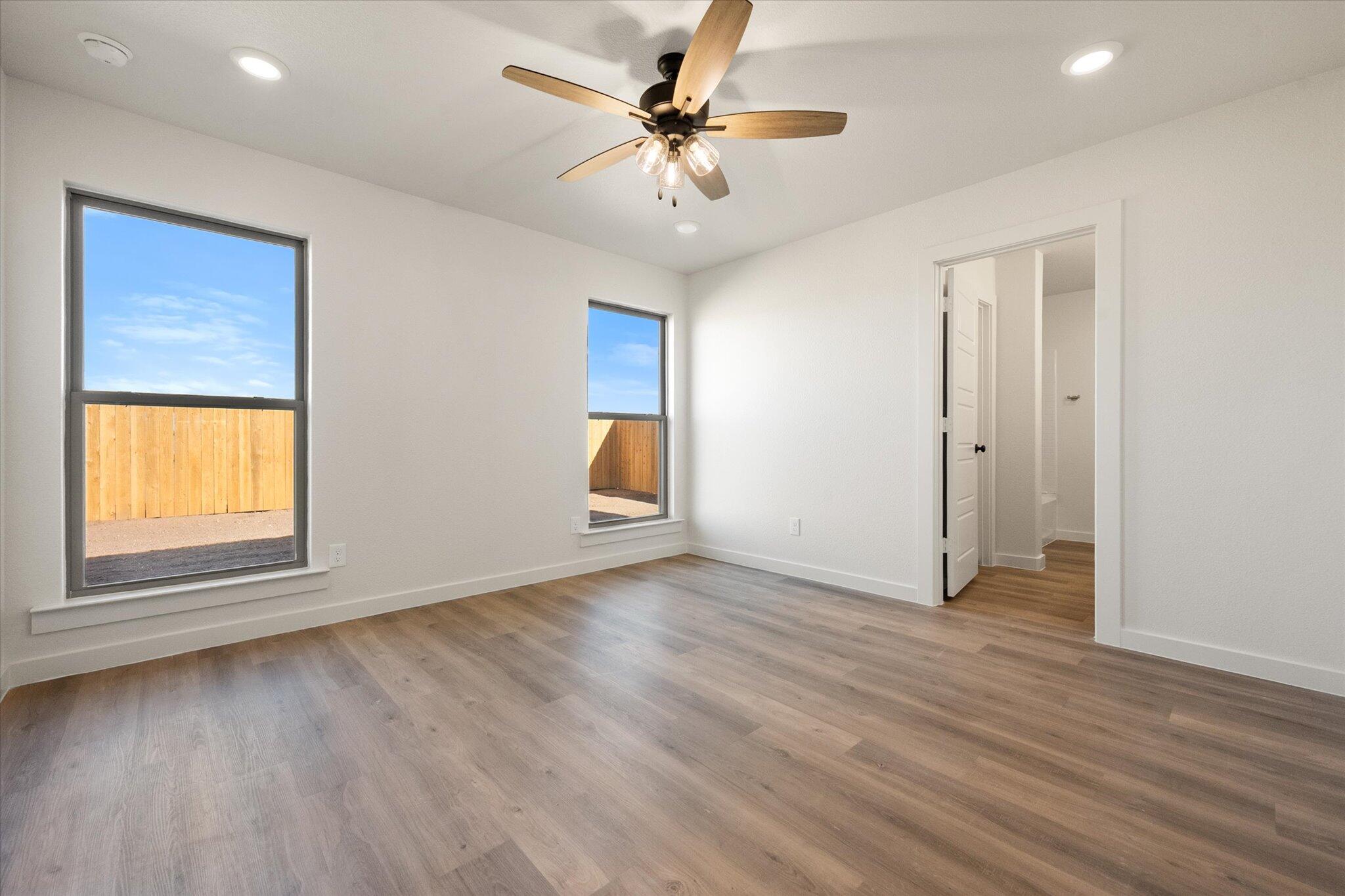 3102 138th Place Lubbock, TX 79423 - Photo 12 of 21 an empty room with wooden floor chandelier fan and windows