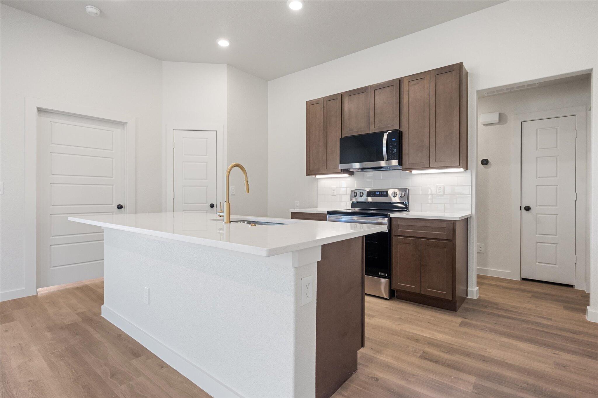 3102 138th Place Lubbock, TX 79423 - Photo 9 of 21 a kitchen with a sink and a stove top oven with wooden floor