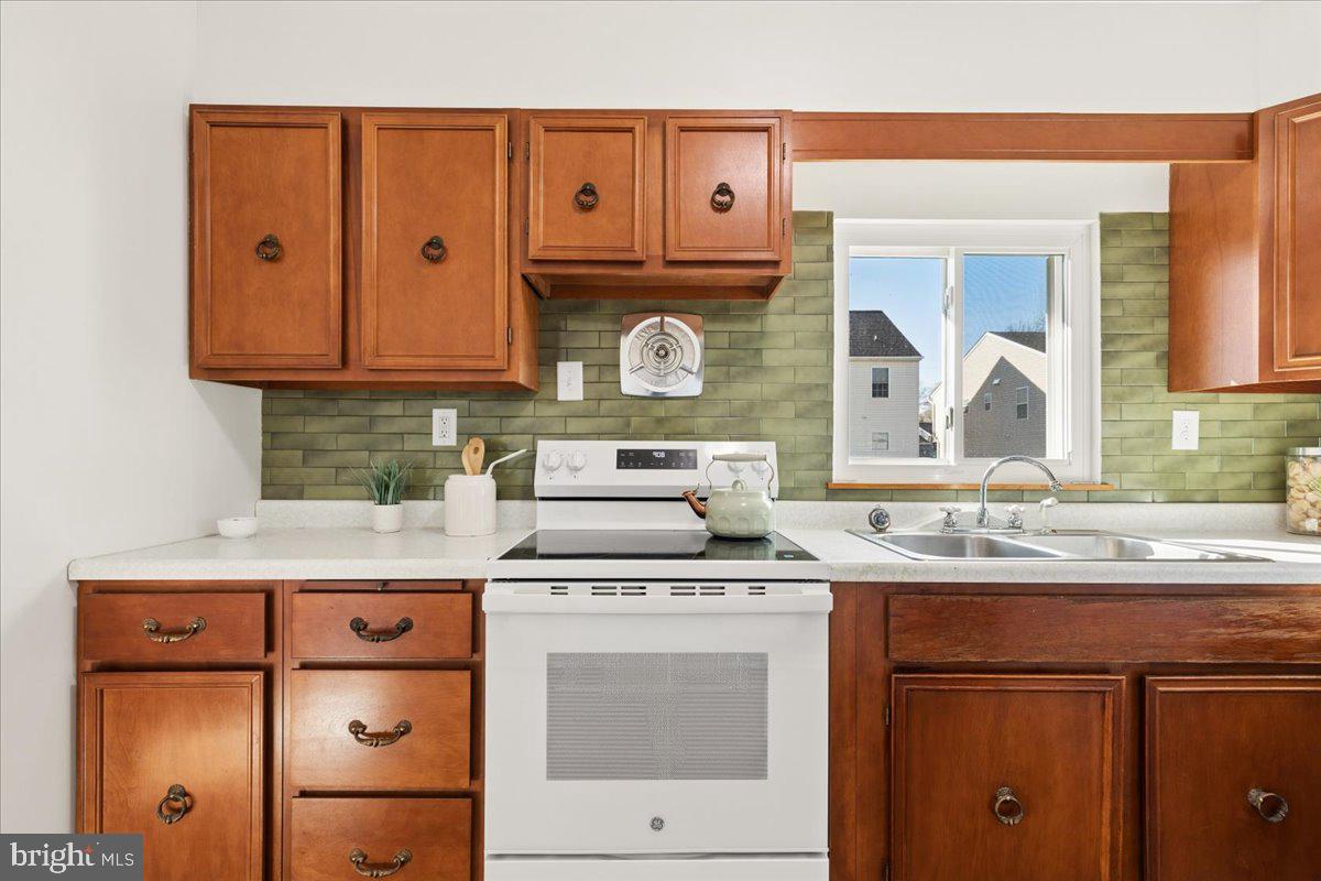 723 207th Street Pasadena, MD 21122 - Photo 14 of 42 a kitchen with granite countertop a sink stove and cabinets