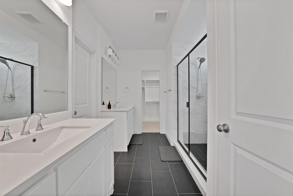 5012 Triadic Lane Prosper, TX 75078 - Photo 18 of 38 Spacious bathroom featuring dual white vanities with integrated sinks, brushed nickel fixtures, a large frameless mirror, and modern tile flooring