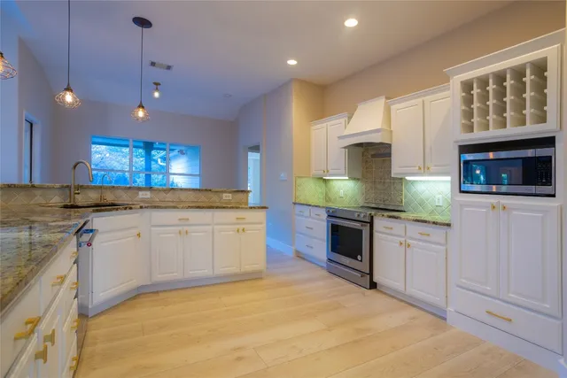 a large kitchen with granite countertop a stove a sink and a granite counter top