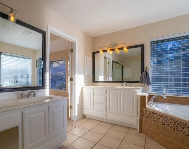 a bathroom with a granite countertop bathtub a sink and a mirror