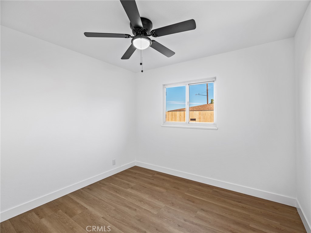 840 East Virginia Way Barstow, CA 92311 - Photo 20 of 35 an empty room with wooden floor ceiling fan and windows