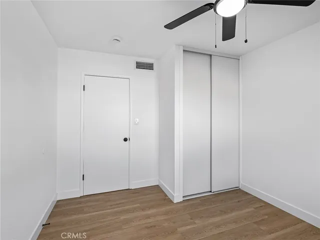 an empty room with wooden floor and ceiling fan