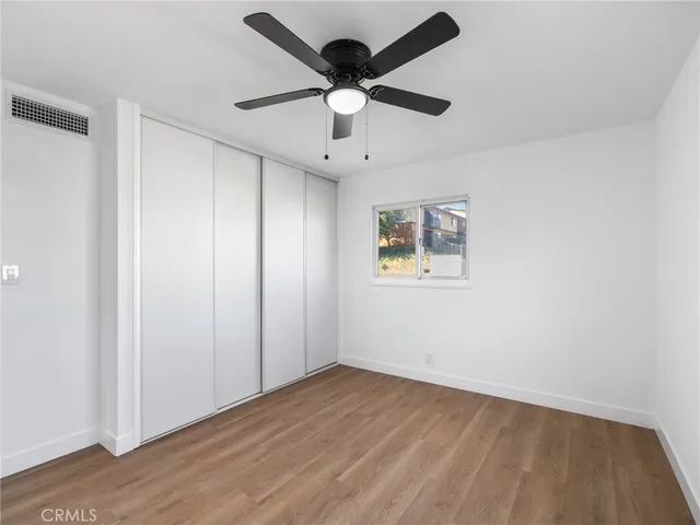 a view of a hallway with wooden floor and a chandelier fan