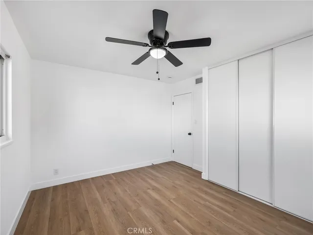 a view of empty room with wooden floor and ceiling fan