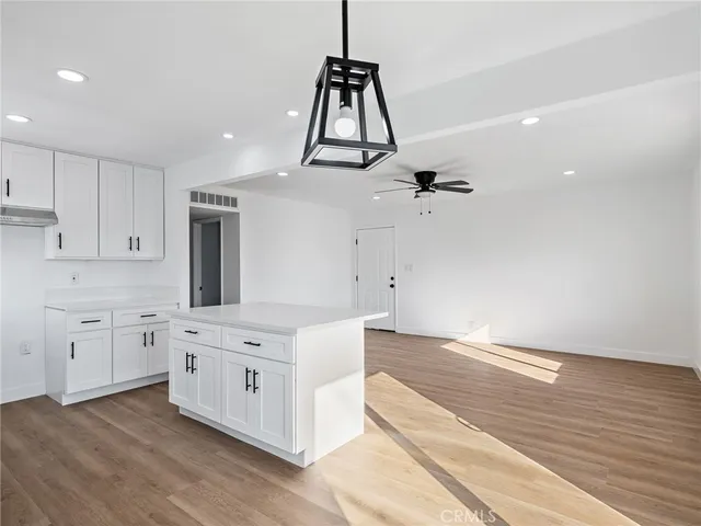 a kitchen with white cabinets and wooden floor