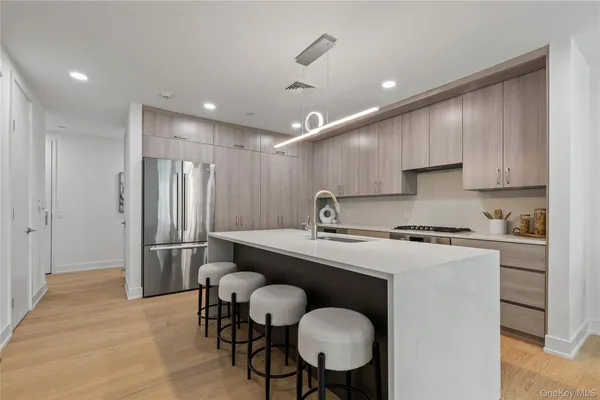 a kitchen with stainless steel appliances granite countertop a sink a stove a refrigerator cabinets and dining table